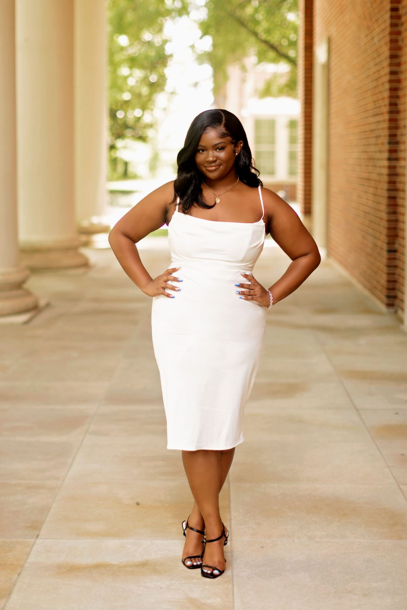 Image of a young Black woman wearing a white dress outside